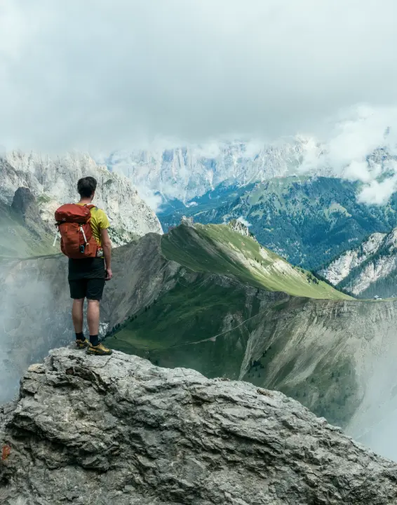 Triumphant hiker atop mountain peak, backpacked, surrounded by breathtaking views.
